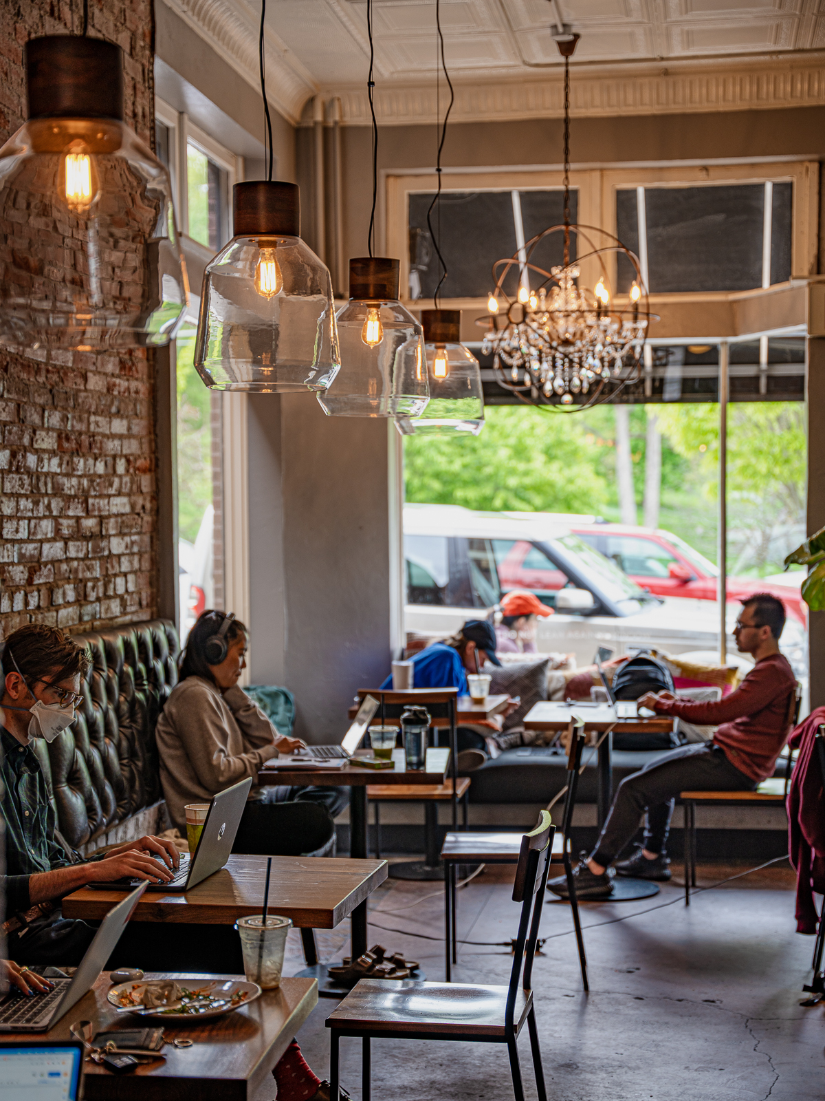 Customers sit inside a Kaldi's Coffee location, many working remotely while enjoying their drinks and food