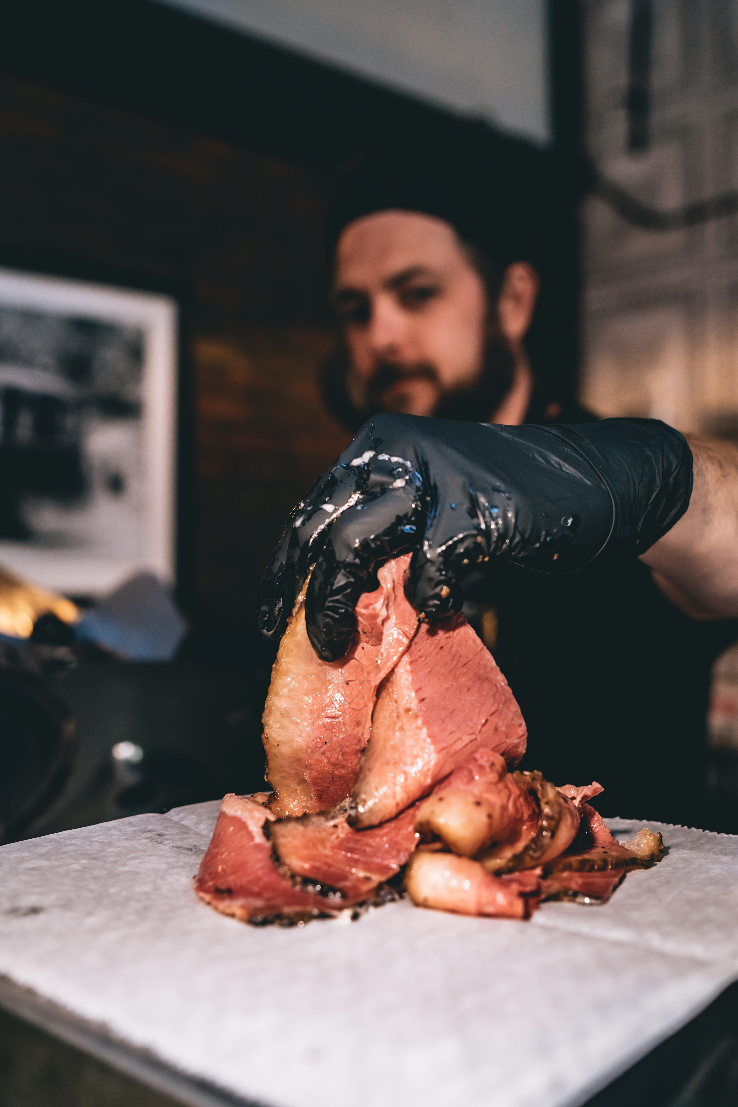 A Mead St. Provisions employee holds a fresh cut of meat with a gloved hand