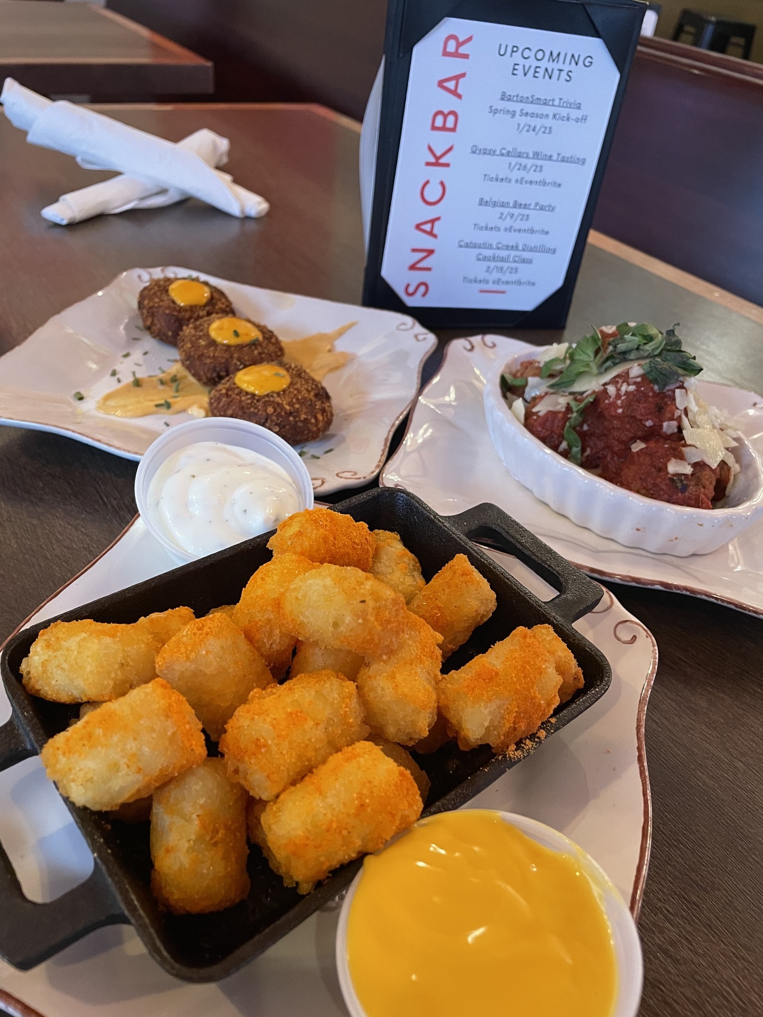 SnackBar menu and plated dishes sit atop a table inside Delirium Café