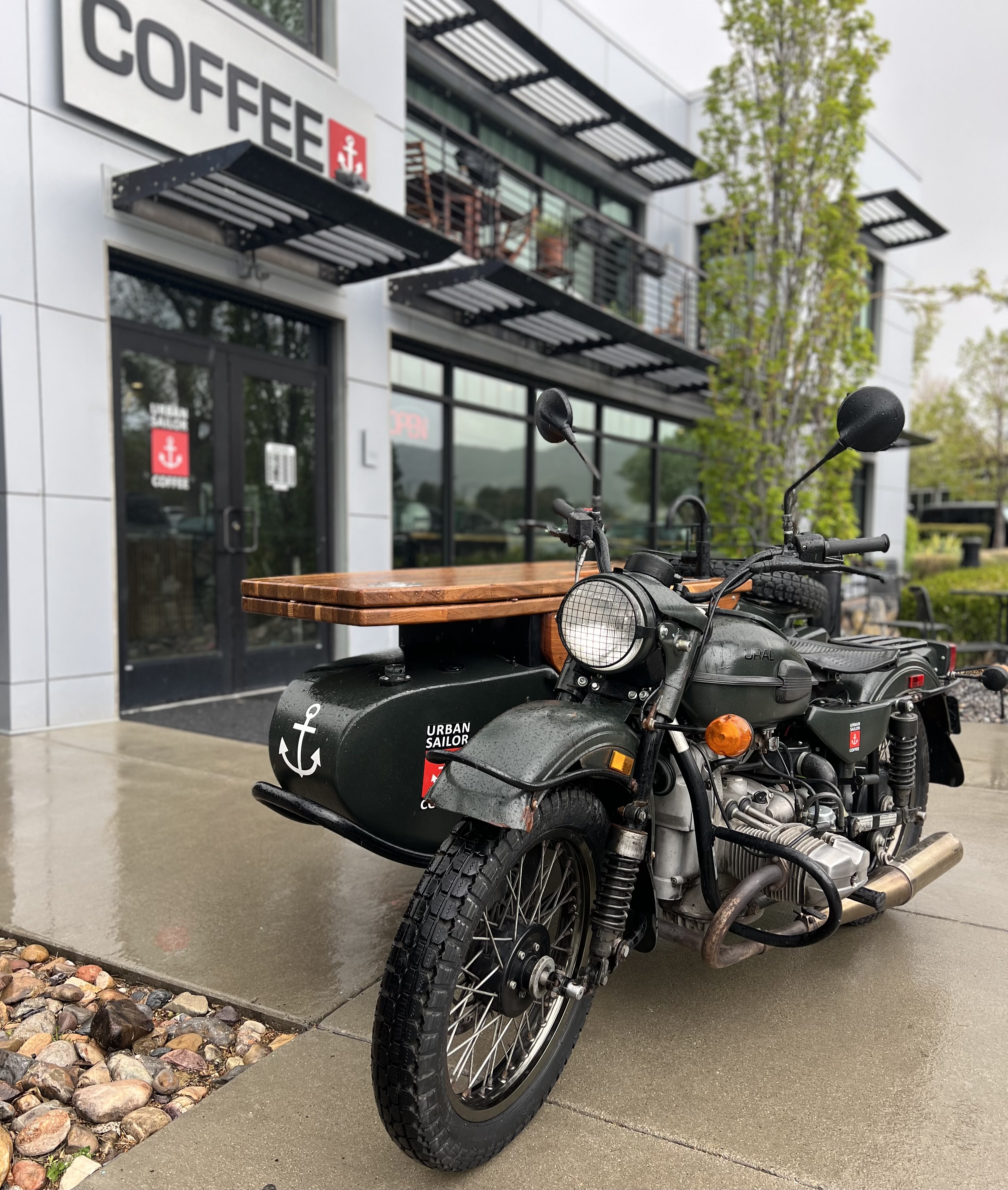 The Urban Sailor motorcycle java cart is parked outside of their brick and mortar cafe location