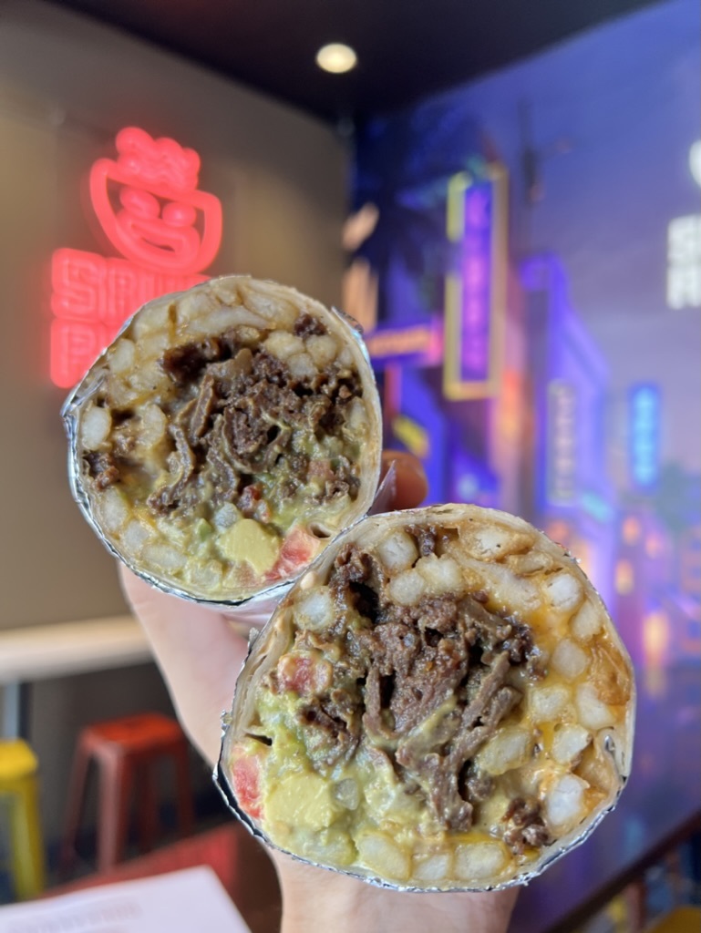 A burrito from Saucy Asian, shown cut in half