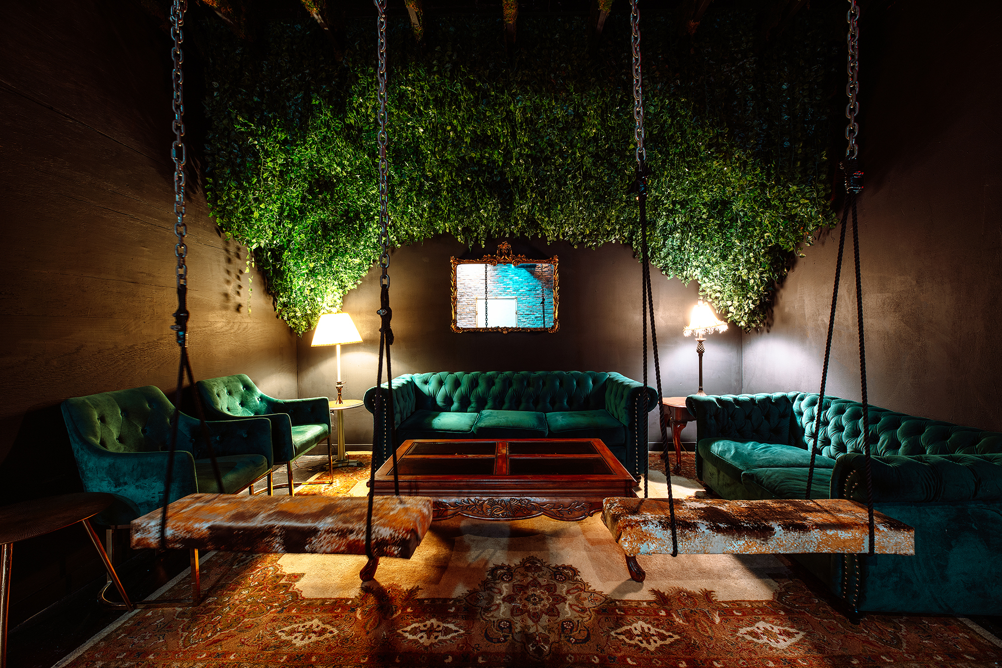 The green area at Savage Labs features green velvet couches, swings, greenery, and ambient lighting.
