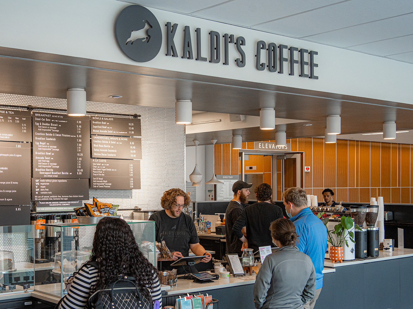 A Kaldi's Coffee cafe counter showing guests placing orders at the Toast terminal